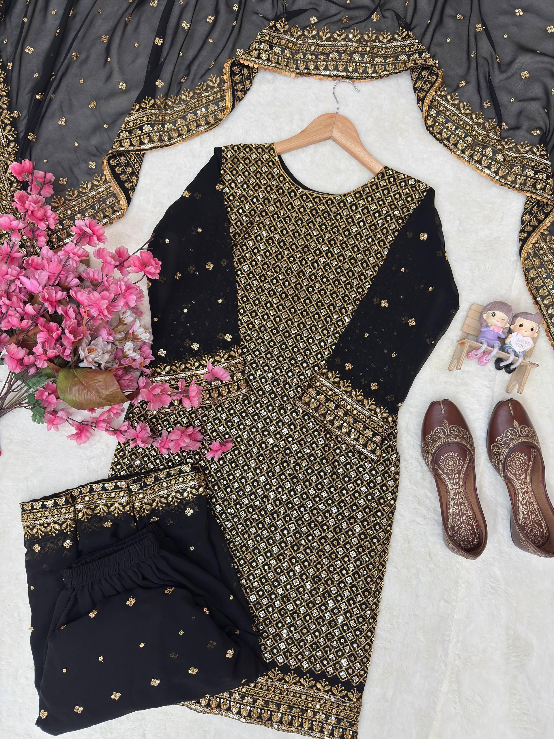 Black and gold traditional outfit with floral arrangement and shoes on a white surface