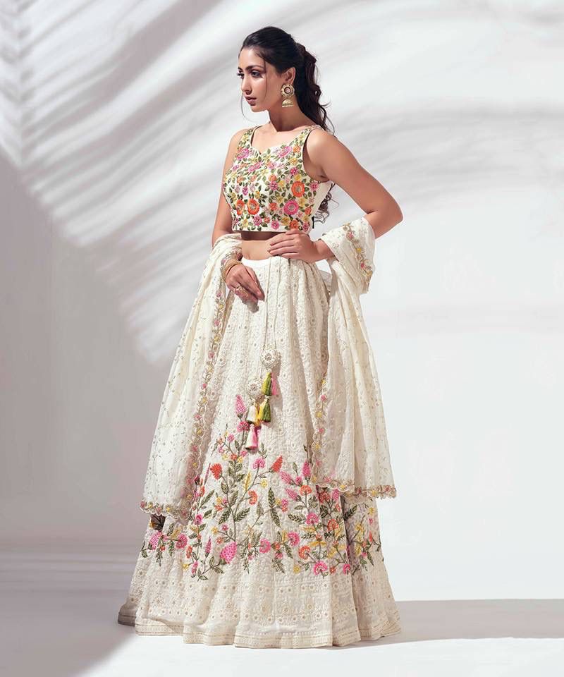Woman wearing a floral embroidered lehenga with a white background