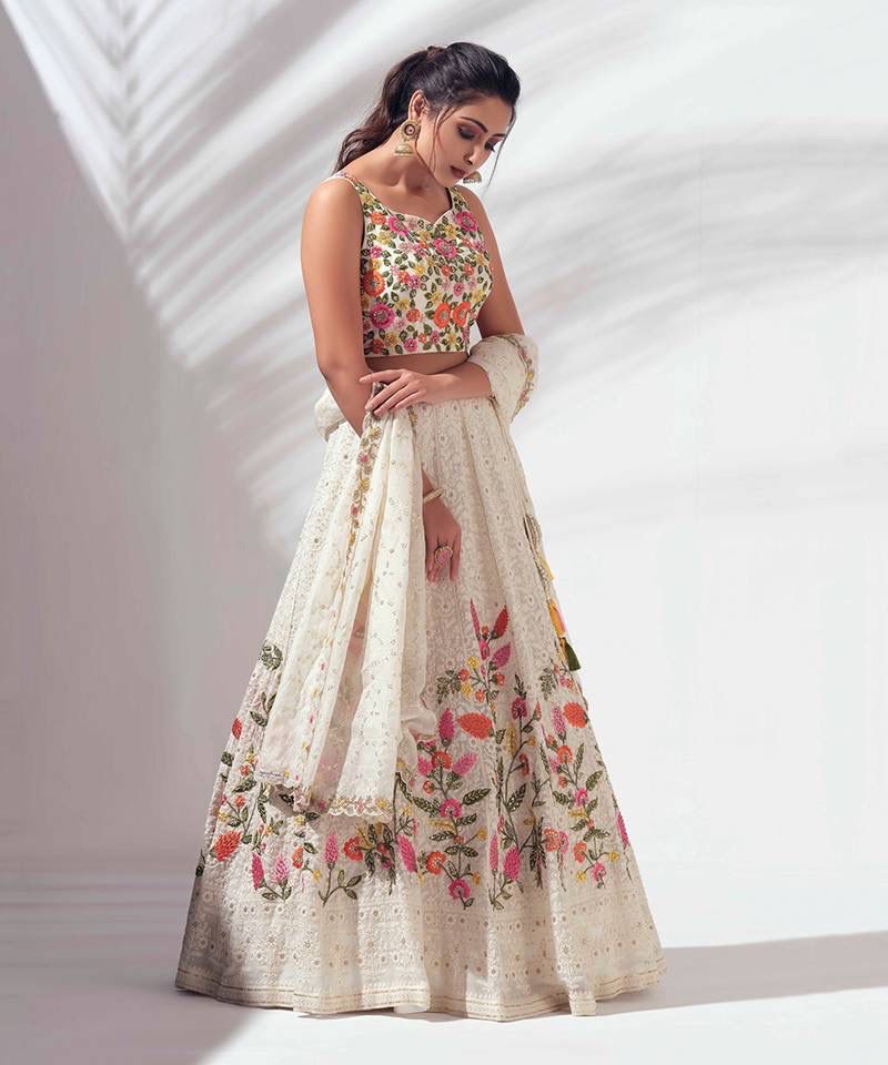 Woman wearing a floral embroidered lehenga with a top against a white background