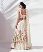 Woman wearing a floral embroidered lehenga with a plain background