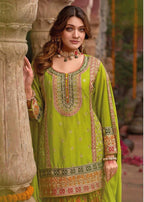 Woman wearing a green embroidered traditional outfit in an outdoor setting.