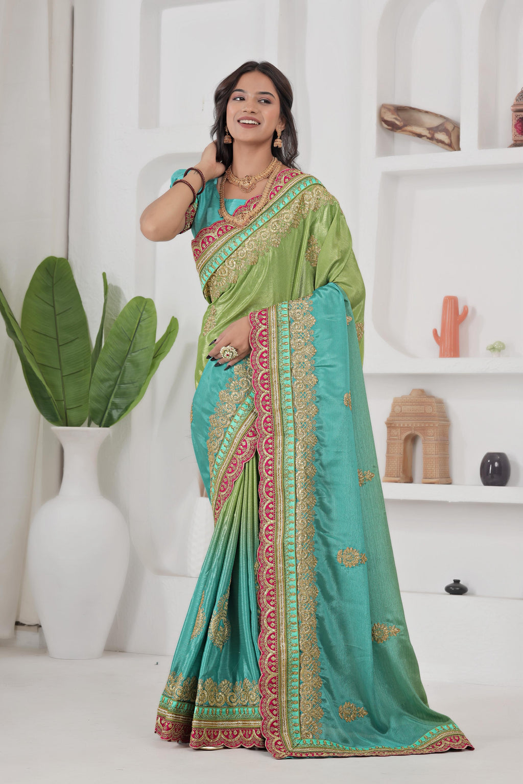 Woman wearing a green and blue saree with a white background