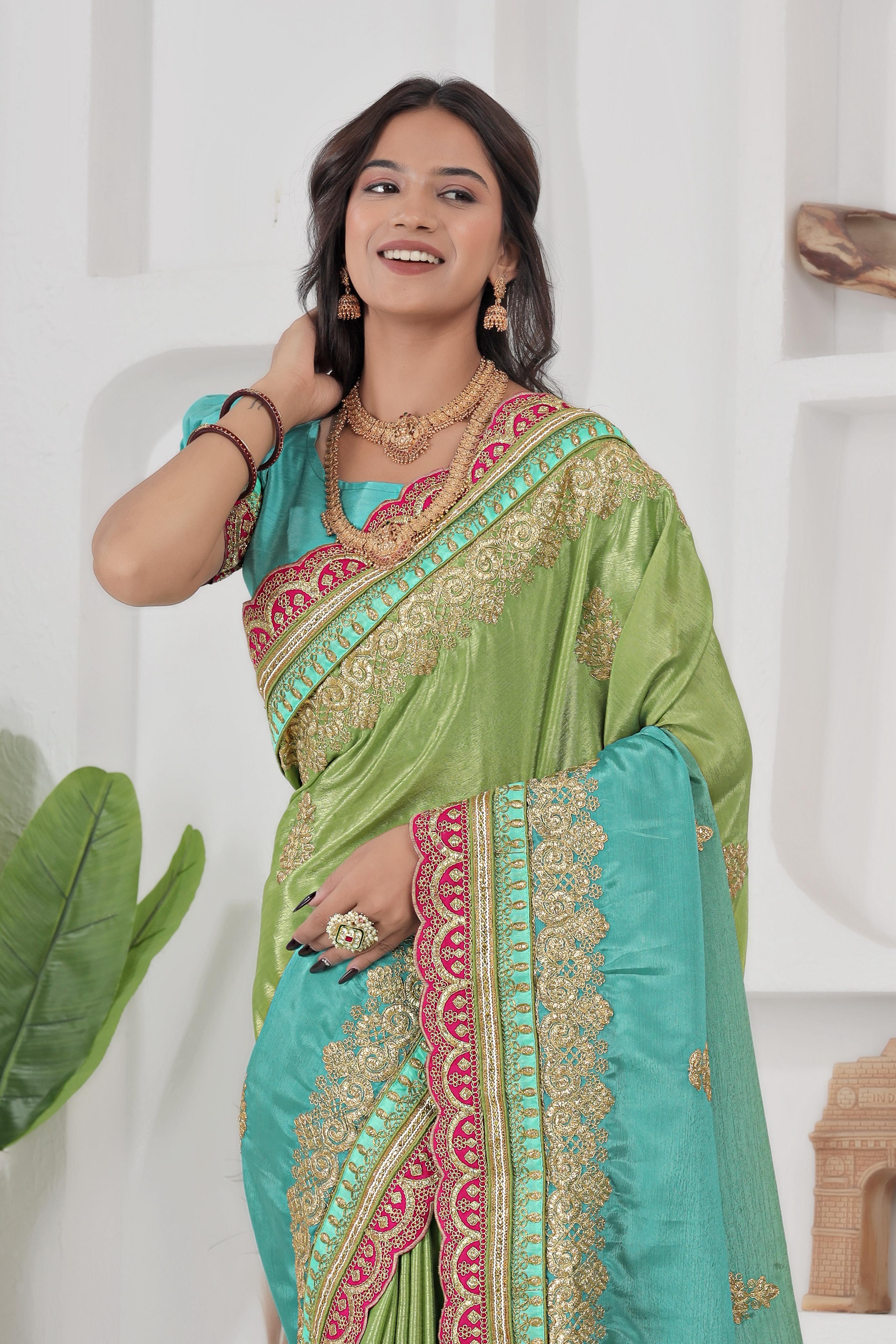 Woman wearing a green and blue saree with intricate patterns, posing against a white background.