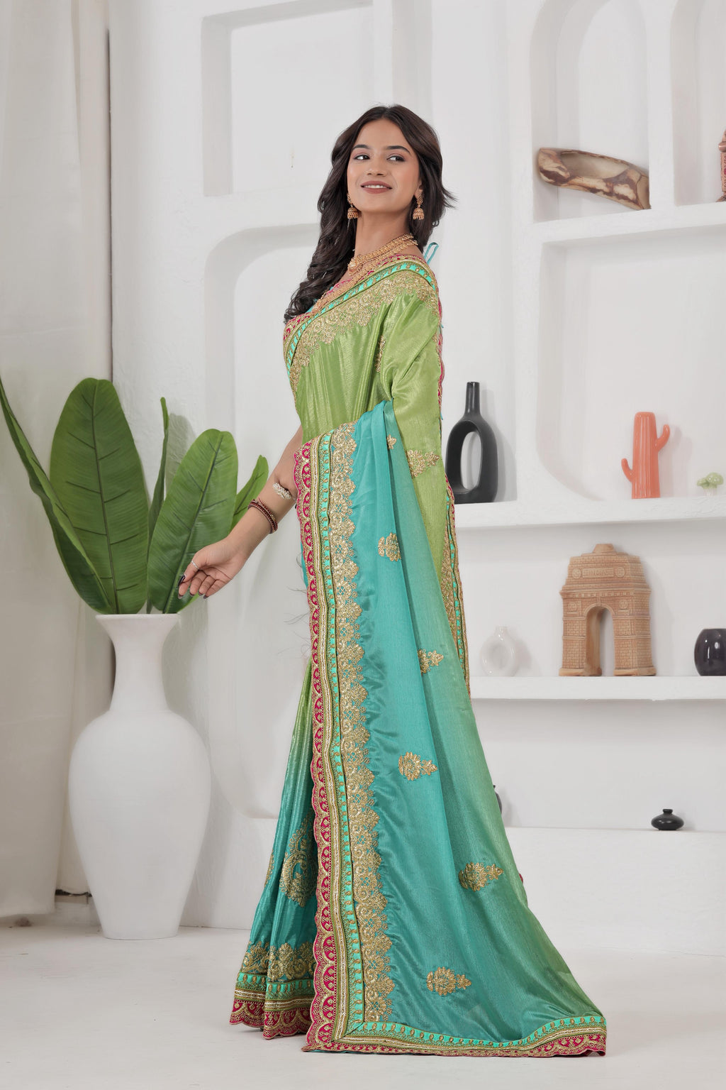 Woman wearing a green and blue saree with a white background