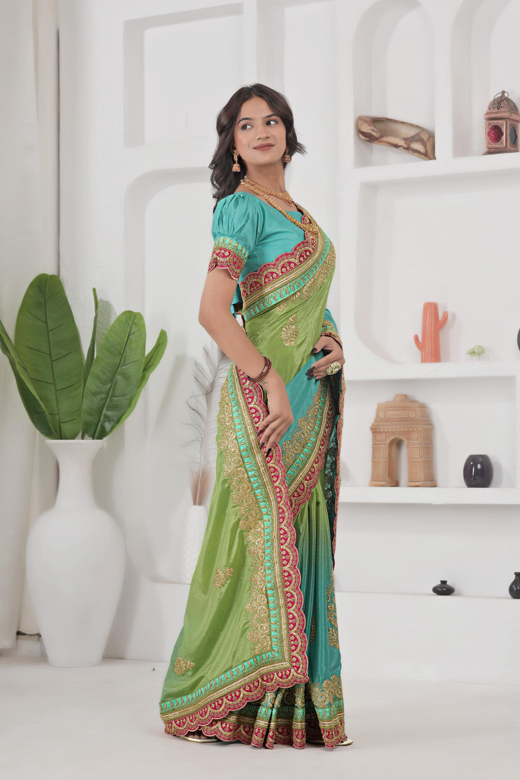 Woman wearing a green and blue saree with a white background