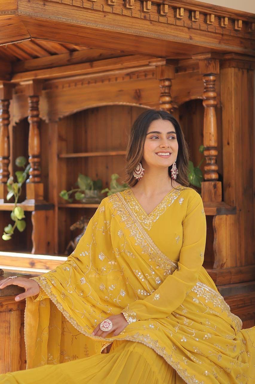 Woman in a yellow saree sitting in a wooden interior setting