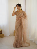 Woman wearing a beige sequin saree in a minimal indoor setting