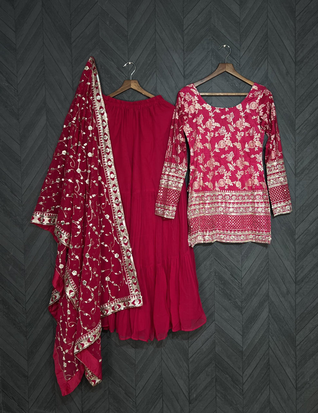 Red traditional outfit with floral patterns on a dark textured background