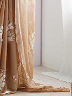 Beige embroidered curtain with floral patterns in a softly lit room.