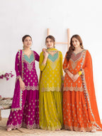 Three women wearing colorful traditional outfits with intricate designs on a white background.
