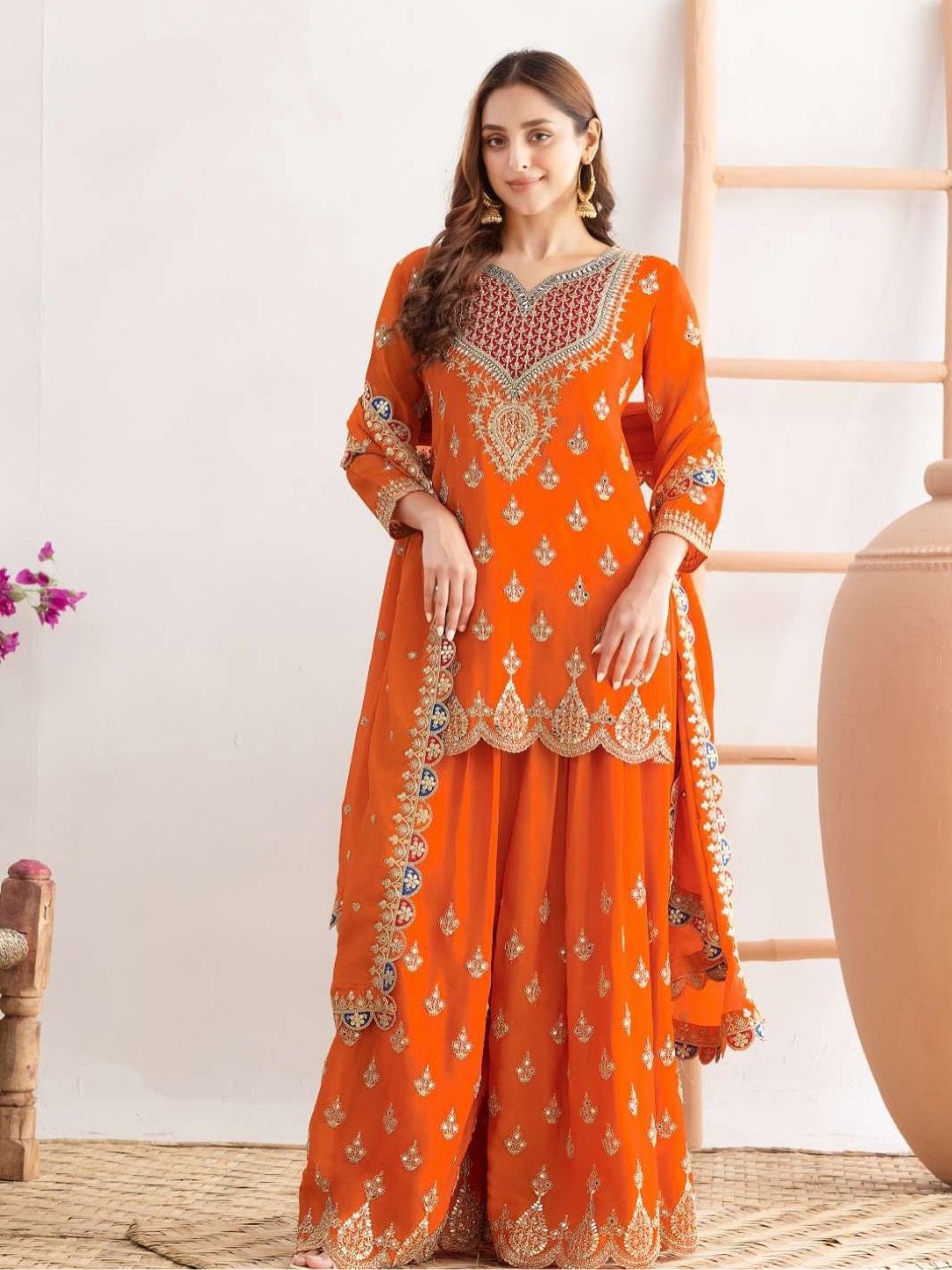 Woman wearing an orange embroidered traditional outfit with a white background