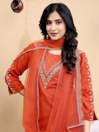 Woman wearing an orange embroidered traditional outfit on a beige background