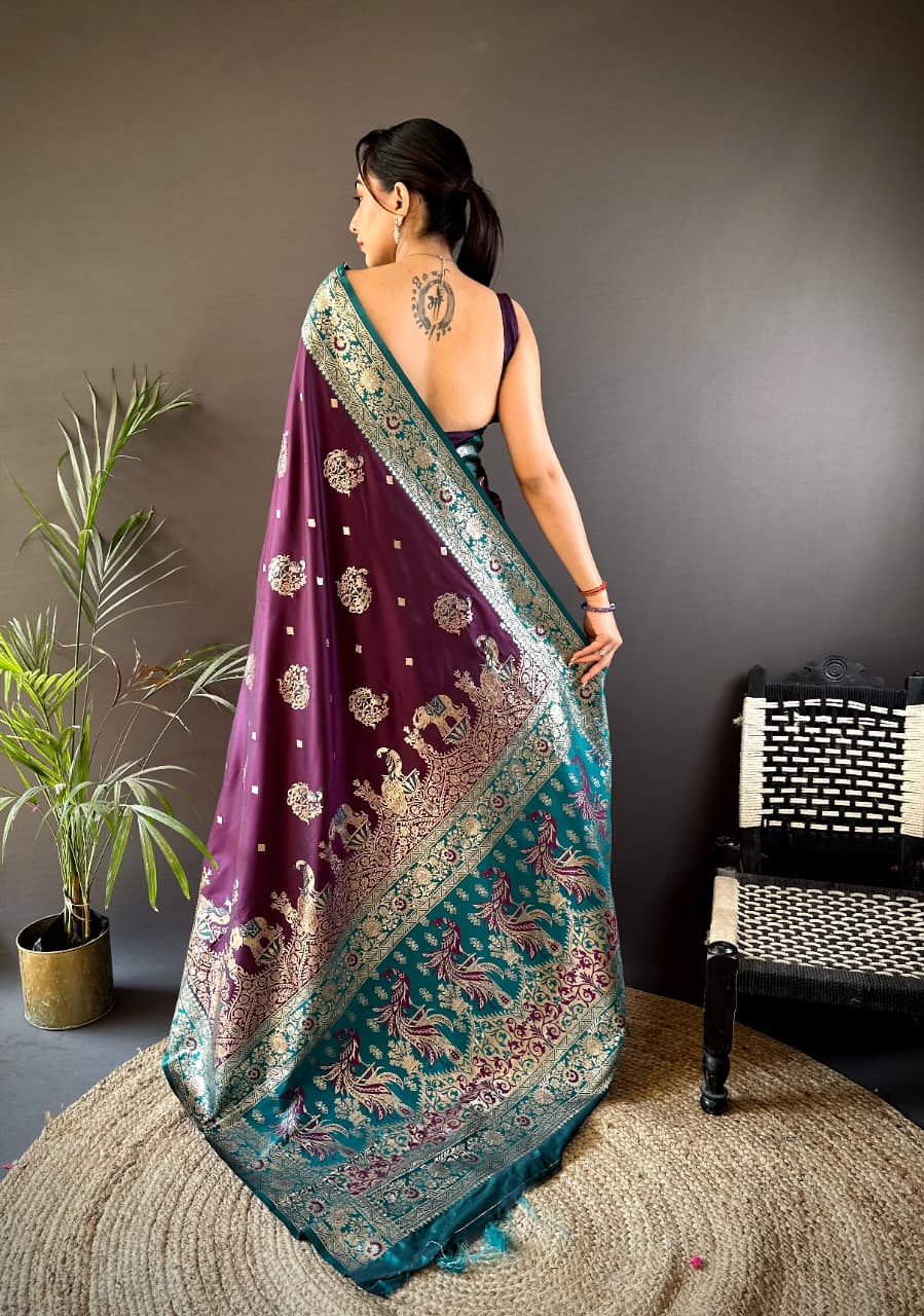 Woman wearing a purple and green saree with a plant and chair in the background