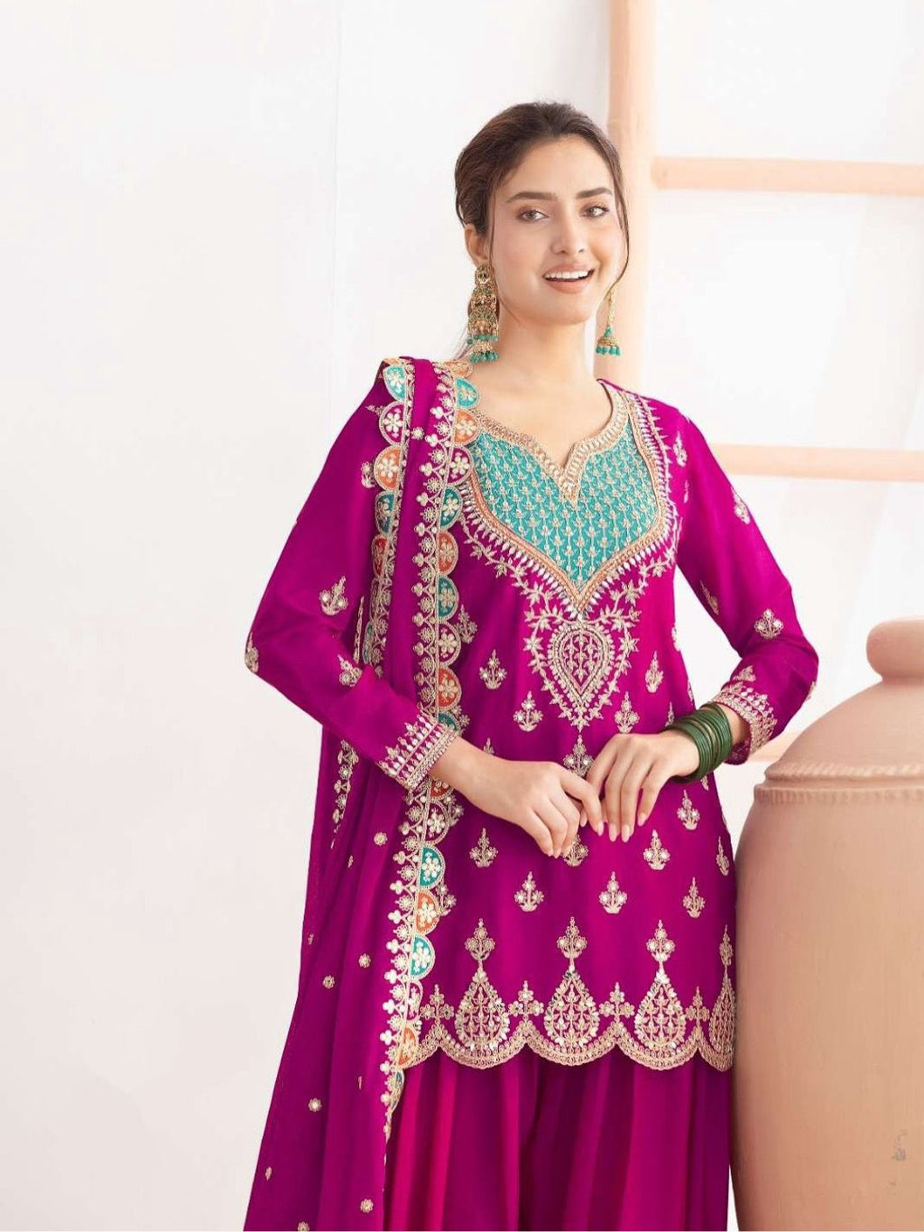 Woman wearing a vibrant purple embroidered traditional outfit with a white background
