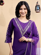 Woman wearing a purple traditional outfit with intricate designs on a beige background