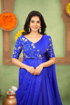 Woman wearing a blue saree with floral patterns against a green background