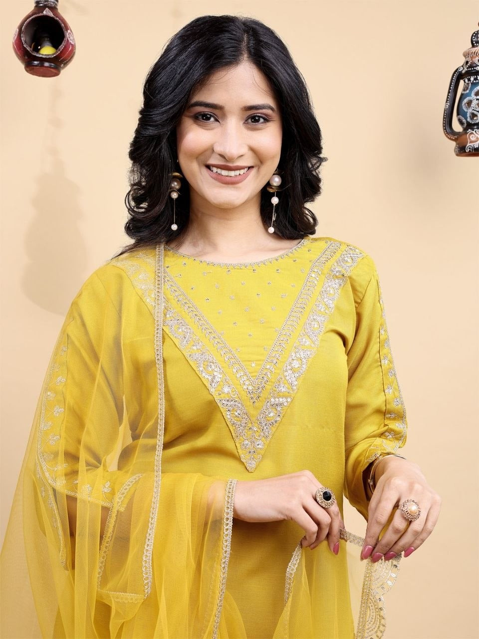 Woman wearing a yellow traditional outfit with intricate designs on a beige background